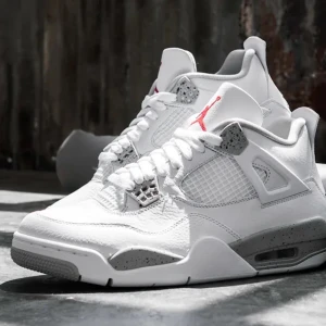 Jordan 4 White Oreo - Snygga Nike Air Jordans i vitt med grå detaljer och röd logga. Skorna har snörning och en stilren design med perforerade paneler och en bekväm sula.