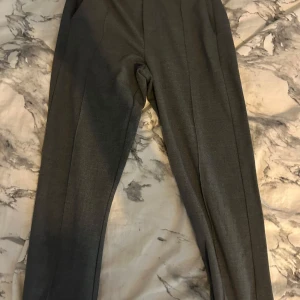 Grå kostymbyxor - Snygga normal midja grå kostymbyxor med en klassisk passform. Perfekta för en stilren look. De har en rak design och är tillverkade i ett bekvämt material. Är tyvärr lite trasiga i botten 