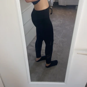 Svarta leggings med meshdetaljer - Snygga svarta leggings med meshdetaljer på benen. Perfekta för träning eller en avslappnad dag. De har en tight passform och är tillverkade i ett stretchigt material för bästa komfort. Det står S/M med de är väldigt tighta så skulle säga att de passar en XS