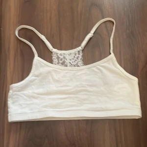 Vit topp/bh med spets  - Säljer en vit topp/bh med spets. Den har ställbara axelband men ingen bh knäppning. Bh-n/toppen är i storlek S och är i mycket bra skick. Lapp med storlek och vilken affär den kommer ifrån är tyvärr bortklippt. Den kommer iallafall antingen från h&m, Lindex eller Kappahl. 