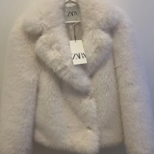 Vit pälsjacka från Zara - Säljer en fluffig och stilren vit pälsjacka från Zara. perfekt för att hålla dig varm. Aldrig använd. Vid snabb affär kan pris diskuteras.
