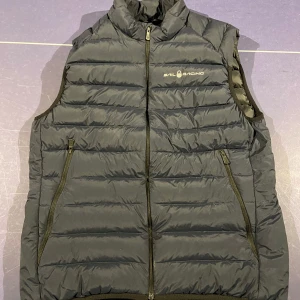 Marinblå dunväst från Sail Racing - Snygg dunväst från Sail Racing i storlek M med dragkedja. En stilren och funktionell väst för alla tillfällen. Använd fåtal gånger