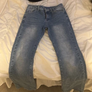 Blå jeans med broderade bakfickor - Snygga blå jeans med broderade detaljer på bakfickorna och en klassisk femficksdesign.  Dragkedja och knapp framtill.