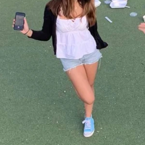 Vit blus med knytband - Söt vit blus med knytband framtill. Perfekt för en avslappnad stil, kan bäras med en kofta eller jacka. Blusen har en luftig passform och är ärmlös.