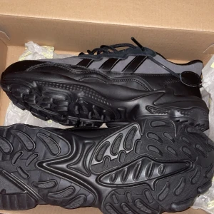 Adidas Ozweego TR i svart - Snygga Adidas Ozweego TR sneakers i svart med en modern design. Skorna har en robust sula och är tillverkade av syntetmaterial. Perfekta för en stilren look. Kan bara mötas upp 