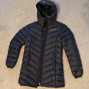 Svart dunjacka från Peak Performance - Snygg svart dunjacka från Peak Performance med huva och dragkedja. 