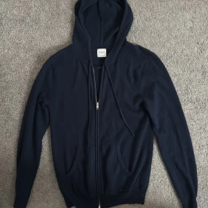 Mörkblå cashmere hoodie med dragkedja - Säljer en stilren mörkblå hoodie från John Henric. Den har en praktisk dragkedja framtill och en klassisk huva med dragsko. Perfekt för en avslappnad look. Nypris 2500: mitt pris 1200