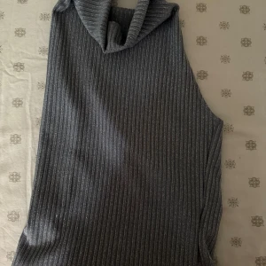 Grå glittrig  ärmlös polotopp - Snygg grå glittrig  ärmlös polotopp med ribbad textur och glittriga detaljer. Perfekt för en stilren look.
