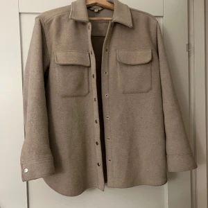 Beige overshirt med knappar - Snygg beige overshirt med långa ärmar och knappar framtill. Storlek 34 men passar även 36.