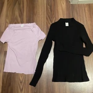 Två toppar från Lindex i lila och svart - Säljer två toppar från Lindex i storlek 146/152. Den lila toppen är kortärmad och ribbad. Den svarta toppen är långärmad och ribbad. (Priset gäller för båda tillsammans) 