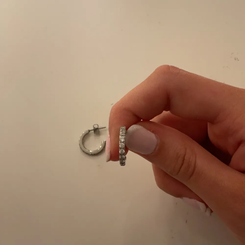 Snyggt smyckeset i silver med en ring och matchande örhängen. Ringen har en unik design med spetsiga detaljer, medan örhängena är små hoops med liknande stil. Perfekt för att ge en edgy touch till din look. . Asusteet.