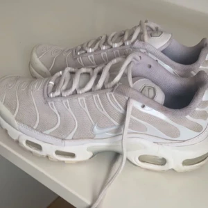 Nike Air Max Plus - Snygga beige Nike Air Max Plus sneakers med vit sula och snörning. Skorna har en snygg design med synliga luftkuddar i sulan för extra komfort. Perfekta för en avslappnad stil.