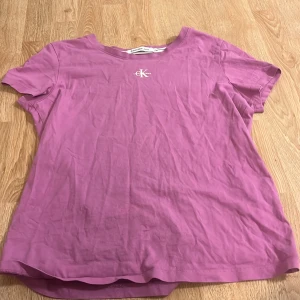Lila t-shirt från Calvin Klein Jeans - Säljer en snygg lila t-shirt från Calvin Klein Jeans med korta ärmar och en liten CK-logga på bröstet. Perfekt för en avslappnad stil.