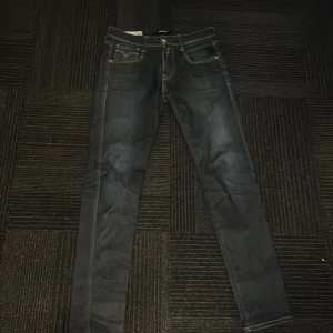 Svarta jeans från Replay - Snygga svarta jeans från Replay med en slim passform. De har klassiska fem fickor och en dragkedja med knappstängning. Perfekta för en stilren look. W29 L32. nypris 900.