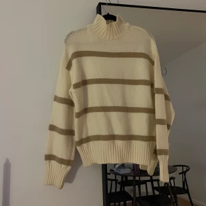 Randig stickad tröja med polokrage - Mysig stickad tröja i beige och vit med polokrage. Tröjan har ett randigt mönster och långa ärmar med ribbade muddar. 🤍🤎