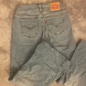 Levis jeans i ljusblå denim - Säljer ett par klassiska Levis jeans i ljusblå denim. De har en rak passform med fem fickor och knappgylf. Perfekta för en avslappnad stil. Använt 1 gång, orginalpris 900. Är 162cm och passar bra.