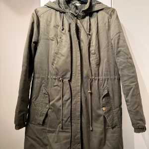 Grön jacka - H&M - En vårjacka med en fin grön färg som är väldigt skön och värmer bra. Jackan är i mycket bra skick och har inga defekter. Den har använts enstaka gånger, ca 4 gånger max och säljs då den inte längre används. Den har guldiga knappar samt guldig dragkedja. Jackan är hyfsat lång och är sann i storleken. Rekommenderar att använda jackan under hösten och våren💗