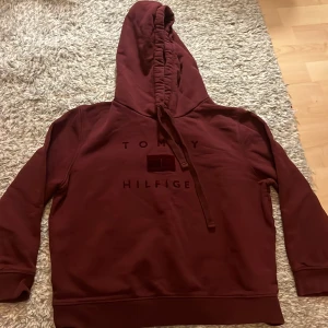 Vinröd hoodie från Tommy Hilfiger - Snygg vinröd hoodie från Tommy Hilfiger med logga. Den har en klassisk design med huva och långa ärmar. Storlek xl men skulle säga att den är lite mindre.