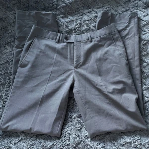 Grå kostymbyxor - Snygga grå kostymbyxor med klassisk passform. Knappar och dragkedja framtill, följer med en extra knapp☺️