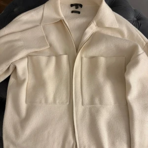 Vit kofta med dragkedja - Säljer en stilren vit kofta från massimo dutti med dragkedja och stora fickor framtill. Koftan har en klassisk krage och ribbade ärmslut. 