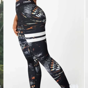 Mönstrade leggings från Stronger - Snygga leggings från Stronger med ett unikt mönster i svart, vitt och orange. De har en hög midja och är perfekta för träning. Materialet är stretchigt och bekvämt, vilket ger en tight passform. Nypris 799 kr.