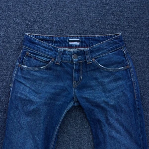 Blå jeans från Tommy Hilfiger - Snygga blå jeans från Tommy Hilfiger. Lågmidjade med en rak/bootcut passform. De är för stora för mig och säljer därför🤍mått på sista bilden! Finns hål på insidan för skosnöre som inbyggt skärp men det påverkar inte hur jeansen ser ut utåt🤍vackra broderier/detaljer på fickorna! Storlek på lappen står w27 l34, skulle säga en s/m