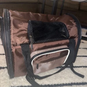 Brun axelväska med nätfickor - Säljer en praktisk  katt/hund väska som kan användas som ryggsäck i brunt syntetmaterial med praktiska nätfickor och dragkedja. Perfekt för att bära med sig det nödvändigaste. Justerbar axelremar för bekväm passform.