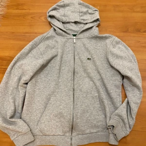 Grå hoodie från Lacoste - Säljer en Lacoste tröja. Nytt skick, 9/10 nypris ca 1300 säljer då den inte kommer till användning. Hör av er vid funderingar.