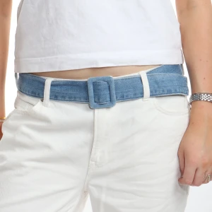 Blått jeansbälte med fyrkantigt spänne - Snyggt blått bälte i jeansmaterial med ett stilrent fyrkantigt spänne. Perfekt för att ge en casual touch till din outfit. Passar bra till både jeans och vita byxor.