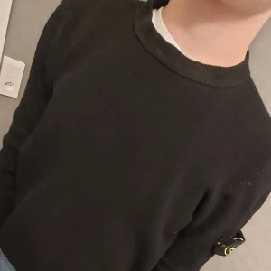 Svart tröja från Stone Island - Säljer denna Snygga  tröja från Stone Island med deras ikoniska märke på ärmen för att den inte kommer till användning längre. Jag är 175 och som ni ser sitter den perfekt samt att skicket är perfekt! Tröjan har en rund hals och är tillverkad i ett ribbat material som ger en stilren look. Perfekt för en casual stil. Pris går att diskutera! 