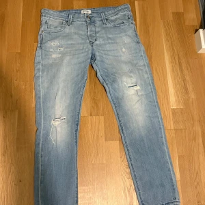 Blå jeans från Jack & Jones - Snygga blå jeans från Jack & Jones i modellen Slim/Glenn. De har en modern slim passform med slitna detaljer och en klassisk femficksdesign. Perfekta för en avslappnad stil.
