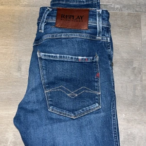 Replay Jeans - Snygga blå jeans från Replay i modellen Anbass. Dessa jeans har en slim fit passform och är perfekta för en stilren look. De har klassiska fem fickor och en dragkedja. Märkeslogga på baksidan ger en extra touch. Storlek 27/32 men är mer som 28/32