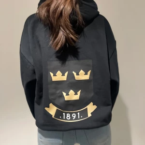 Svart hoodie med aik tryck  - Snygg svart hoodie med tryck på ryggen. Hoodien har en klassisk passform och en bekväm huva.