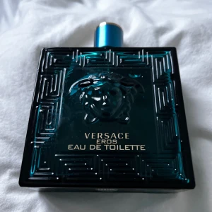 Versace Eros Eau de Toilette 200ml - Säljer en flaska Versace Eros Eau de Toilette. Flaskan är elegant i en djupblå färg med ett grekiskt mönster och Medusa-huvud på framsidan. Den rymmer 200 ml av denna ikoniska doft.