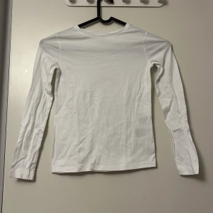 Vit långärmad tröja från H&M - Säljer en klassisk vit långärmad tröja från H&M. Perfekt basplagg för alla tillfällen. Tillverkad i mjukt material för extra komfort. Passar utmärkt till lager-på-lager-stil eller som den är.