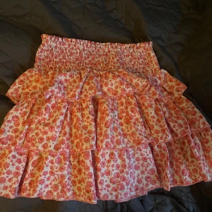 Blommig volangkjol från Shein - Söt blommig volangkjol från Shein i rosa och vit. Kjolen har flera lager volanger och en elastisk midja för bekväm passform. Perfekt för en somrig look!