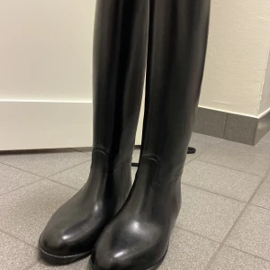 Svarta höga ridstövlar - Snygga svarta höga ridstövlar i ett stilrent och klassiskt utförande. Perfekta för både regniga och kyliga dagar. Helt oanvända o nya 
