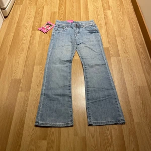 Lågmidjade bootcut jeans  - Ljusblåa lågmidjade bootcut jeans med detaljer på fickorna i stretchiga material. Midjemått rakt över 30cm, innerbenslängd 67cm. Har inga bilder på då dessa är ganska små, står strlk 23 på taggen💞