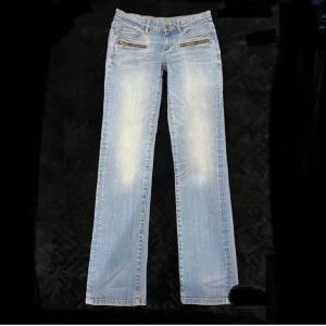 Ljusblå jeans med dragkedjedetaljer - Snygga ljusblå jeans med coola dragkedjor framtill. De har en klassisk femficksdesign och dekorativa sömmar på bakfickorna. Perfekta för en avslappnad stil! Köpte på Plick men säljer då de var för små för mig. Skriv för fler frågor🩷💓