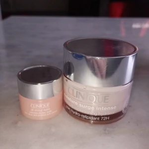 Clinique Moisture Surge Intense - Säljer två återfuktande krämer från Clinique. Den större burken är Moisture Surge Intense 72H, perfekt för torr hud. Den mindre burken är en ögonkräm, också från Clinique, som ger extra fukt och fräschör. Båda har en lyxig känsla med silverlock och är idealiska för daglig användning.