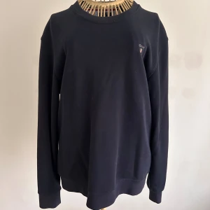 Mörkblå sweatshirt från GANT - Säljer en stilren mörkblå tröja från GANT i bra skick. Den har en klassisk design med rund hals. Diskret GANT-logga på bröstet. Passar perfekt till höst och vår! Storlek 170