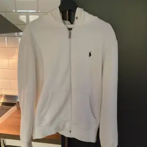 Vit Ralph Lauren Zip up. Använd fåtal gånger men har inga defekter! Storlek är M och är köpt från Zalando. Snören från tröjan ingår. Frågor eller funderingar hör gärna av dig.