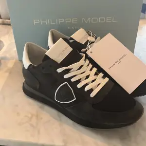 Snygga svarta sneakers från Philippe Model i nytt skick. De har en stilren design med vita snören och vita detaljer på hälen. Kommer i originalförpackning. Pris kan diskuteras vid snabb affär.