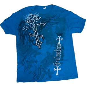 Fet blå drainer t shirt - Säljer en cool blå t-shirt med ett stort korsmotiv och texten 'salvation' på framsidan. Perfekt för en avslappnad stil. (Vet inte märke)