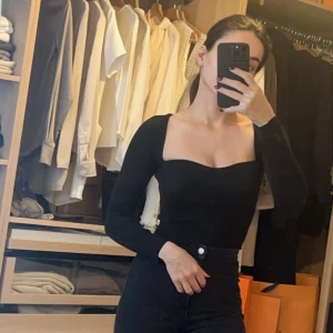 Svart långärmad topp - Snygg svart långärmad topp med en tight passform. Perfekt för både vardag och fest. Toppen har en enkel och stilren design som gör den lätt att matcha med olika outfits.