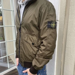 Olivgrön Stone Island jacka - Hejsan, Säljer min stilrena Jacka i det trendiga märket Stone Island. En olivgrön färg och i storleken M. Obs på dom två sista bilderna ser du två defekter med jackan men dom går lätt att fixa om man vill men annars är de inget man tänker på . Har själv aldrig varit med om någon som märkt dom. Går även att veckla in och ut luvan beroende på om man vill att den ska synas eller inte. Skriv vid fler eventuella frågor eller funderingar. 🌟