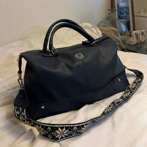 Mörkblå axelväska/weekendbag från NYPD - Säljer en snygg mörkblå axelväska från NYPD i mycket bra skick. Väskan har ett coolt mönstrat axelband och är perfekt för både vardag och resa. Den har en dragkedja upptill och flera fack inuti för smart förvaring. Perfekt för dig som vill ha stil och funktion i ett!