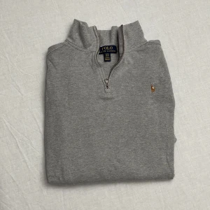 Grå tröja med dragkedja från Polo Ralph Lauren - Säljer en stilren grå tröja från Polo Ralph Lauren. Den har en halv dragkedja och det klassiska broderade logotypen på bröstet. Perfekt för både vardag och lite finare tillfällen. Tröjan är i bra skick och passar perfekt till höst och vår. Strl xl barn vilket motsvarar ca xs-s 