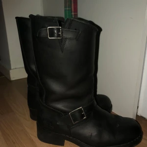 Svarta boots från Johnny bulls  - Säljer ett par svarta fodrade boots från Lucky Brand i mycket bra skick. De är gjorda av skinn och har en robust sula med bra grepp. Bootsens design inkluderar spännen som ger en cool look. Perfekta för höst och vinter!