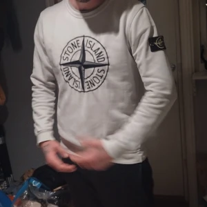 Vit sweatshirt från Stone Island( byten är intressant) - Säljer en snygg vit sweatshirt från Stone Island med deras ikoniska logga tryckt på framsidan (brodering). Perfekt för en casual look och passar bra till både jeans och joggers. Tröjan är i bra skick och har en normal passform . Large. Perfekt för höst och vår! Ursäkta bilderna men tar nya ifall de behövs vid intresse ! Nypriset va 3800 (är idag 4000)